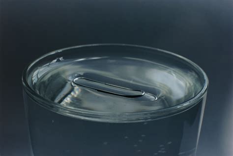 Surface tension is the property of a liquid that causes its surface to behave like a stretched elastic membrane. It is the result of cohesive forces between adjacent molecules at the liquid-air interface, creating a tendency for the surface to minimize its area and resist external forces. 
